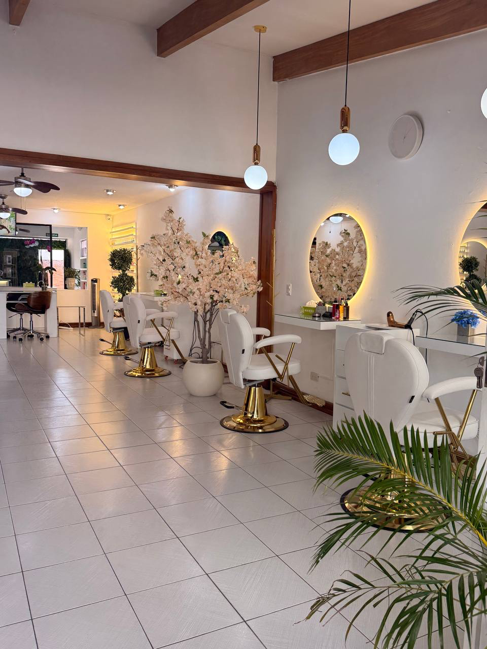 Vista panorámica del salón Unique Beauty Designers con estaciones blancas y detalles dorados.